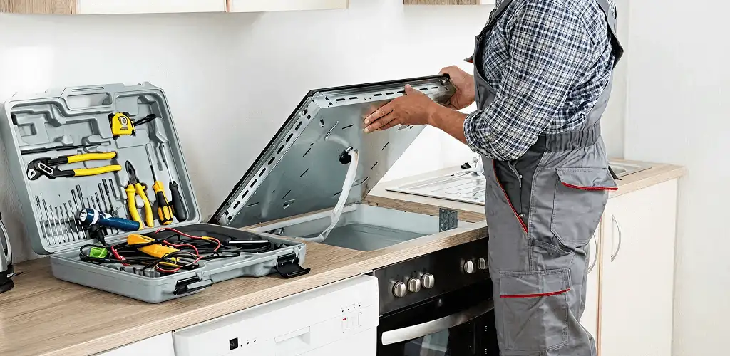 Handyman repairing a cooktop and checking wiring connections in Des Moines, IA