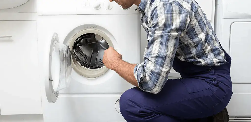 Handyman inspecting a dryer drum and internal parts for repair in Des Moines, IA