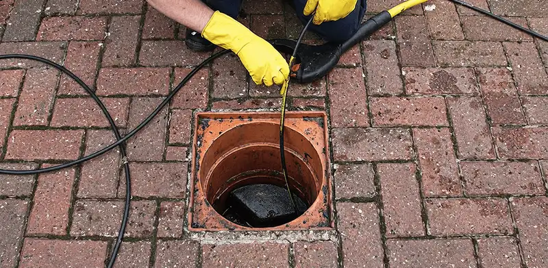 Drain cleaning technician using a drain snake to clear a clogged drain in Des Moines, IA
