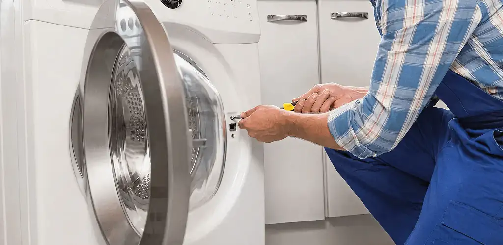 Handyman repairing a clothes dryer and checking electrical connections in Des Moines, IA