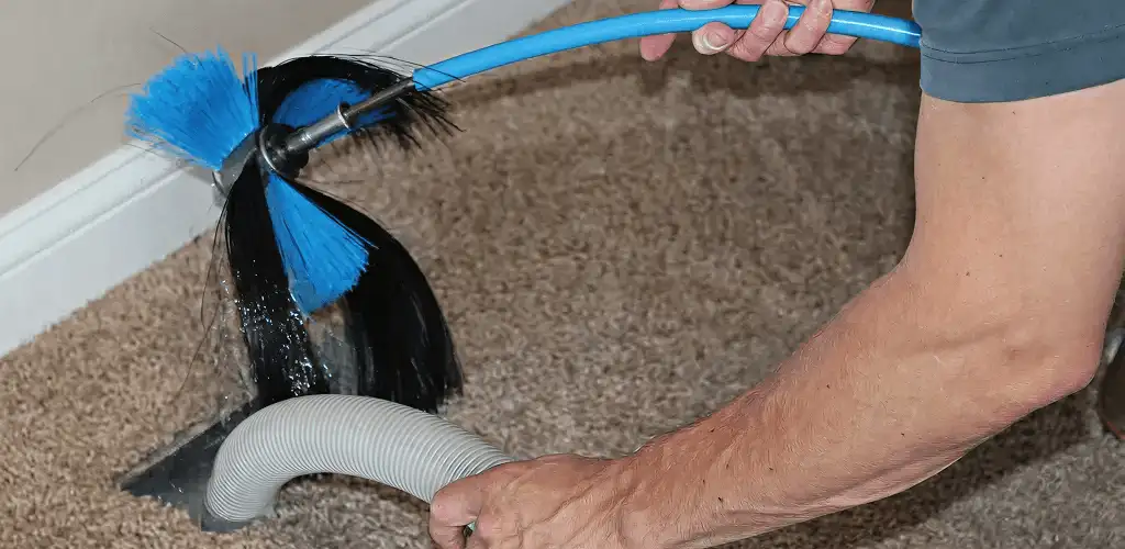 Dryer vent cleaning technician brushing lint from a vent line in Des Moines, IA