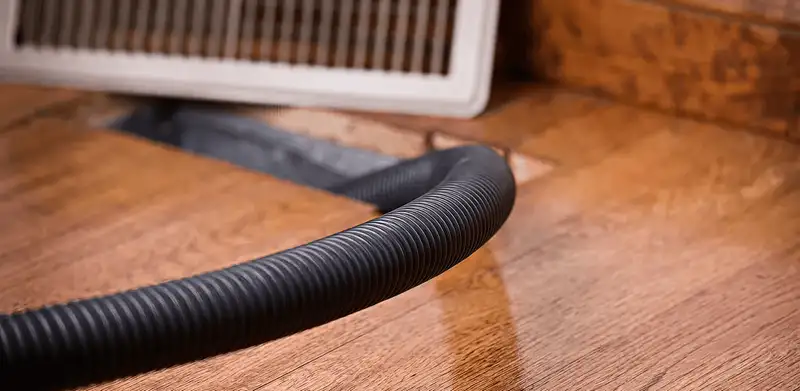 Air duct cleaning hose inserted into a floor vent for ductwork cleaning in Des Moines, IA