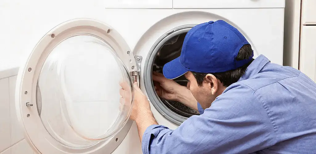 Washing machine repair handyman inspecting a front-load washer drum in Des Moines, IA