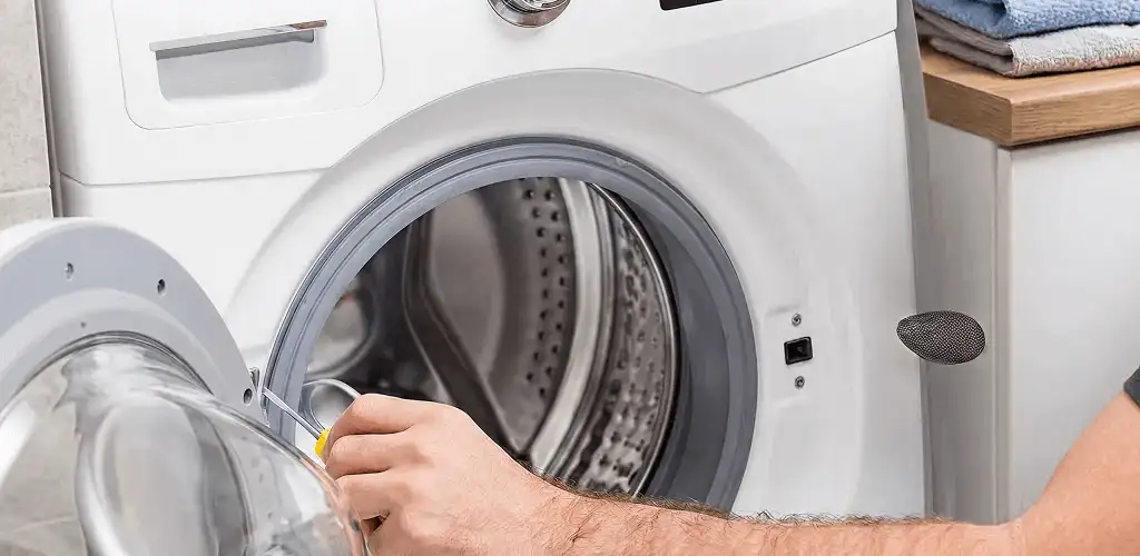 Handyman repairing a front-load washing machine and inspecting the drum in Des Moines, IA
