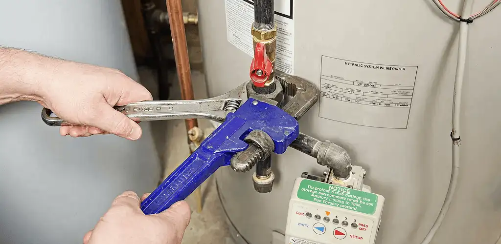 Water heater repair technician tightening the shutoff valve and supply line in Des Moines, IA